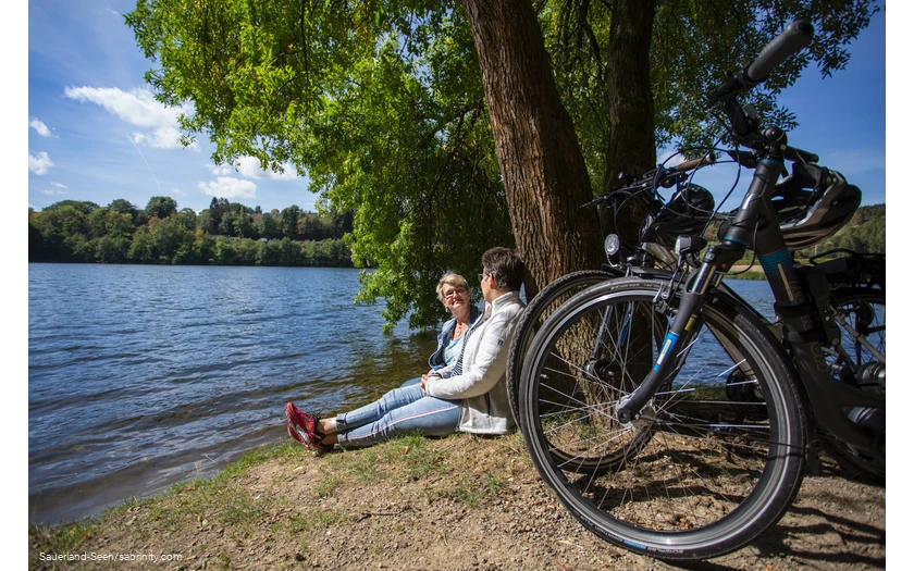 Zwei Frauen mit ihren Rädern machen eine Pause am Seeufer