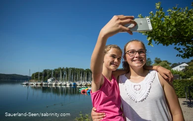 Zwei junge Mädchen machen ein Selfie am Seeufer