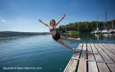 Mädchen lässt sich am Sorpesee vom Steg ins Wasser fallen