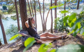 Frau lehnt sich an einen Stamm und genießt die Natur