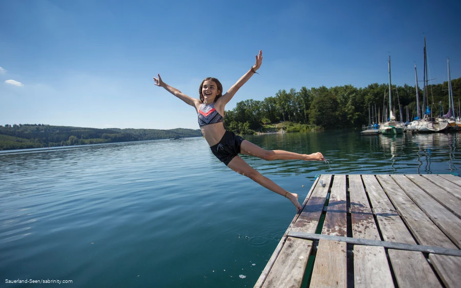 Mädchen lässt sich am Sorpesee vom Steg ins Wasser fallen