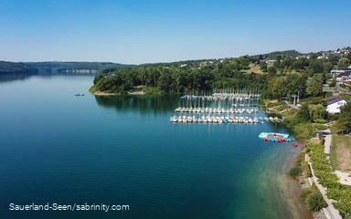 Drohnenaufnahme vom glasklaren blauen Wasser mit Segelbooten im Hintergrund