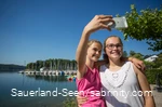 Zwei junge Mädchen machen ein Selfie am Seeufer