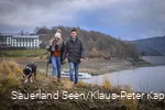 Ein Paar geht mit Hund am Hennesee spazieren.