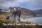 Ein Paar geht mit Hund am Hennesee spazieren.