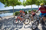 Familie fährt auf Mountainbikes über die Promenade am See